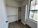 Well-lit walk-in closet with custom shelves and wood closet rods near a bright window at 6040 Scalybark Road, Durham, NC 27712