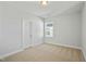 Well-lit bedroom featuring neutral carpeting, white door, and window at 441 Edison Rail Ln, Knightdale, NC 27545