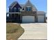 Beautiful two-story home featuring stone accents, attached garages, and manicured lawn on a sunny day at 271 White Azalea Way, Homesite 30, Benson, NC 27504