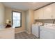 Well-lit laundry room with machines, cabinets and black and white patterned floor tiles at 271 White Azalea Way, Homesite 30, Benson, NC 27504
