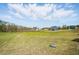 Expansive backyard view of a blue home with mature trees and pond in the distance at 3804 Cobbler View Way, Fuquay Varina, NC 27526