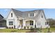 Beautiful white brick home with a covered porch, black railings, manicured lawn, and a pond view at 3804 Cobbler View Way, Fuquay Varina, NC 27526