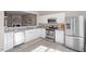 Well-lit kitchen featuring white cabinets, stainless steel appliances, gray counters, and wood-look floors at 610 Canyon Lake Cir, Morrisville, NC 27560