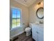 Bright bathroom featuring a white vanity, round mirror, and a window view at 7553 Sweetwater Dr, Nashville, NC 27856