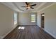 Spacious bedroom with tray ceiling, fan, luxury vinyl floors, and natural light from two windows at 7553 Sweetwater Dr, Nashville, NC 27856