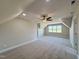 Expansive bonus room featuring plush carpet, neutral paint, ceiling fan, and natural light at 7553 Sweetwater Dr, Nashville, NC 27856