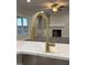 Close-up of kitchen island with quartz countertop and golden faucet; living room in the background at 7553 Sweetwater Dr, Nashville, NC 27856