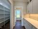 Pantry with white cabinets, drawers, tile backsplash, and view to bathroom with outside view at 7553 Sweetwater Dr, Nashville, NC 27856