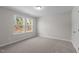 A sunlit bedroom boasts neutral walls, plush carpet, and a double window framing lush greenery at 317 Highland Ridge Ln, Knightdale, NC 27545