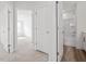 Hallway with white doors leading to a bathroom with tub/shower and bedroom with natural light at 53 Lavender Ln, Clayton, NC 27520