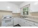 A bright kitchen featuring white cabinets, updated countertops, a sink, and a white appliance at 320 Zollicoffer Ave, Henderson, NC 27536