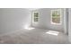 Sunny bedroom with neutral carpet, white walls, and two windows offering a view of the surrounding trees at 35 Accord Dr, Youngsville, NC 27596