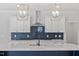 Close-up of a kitchen featuring a navy island, quartz countertops, white cabinets, and herringbone backsplash at 35 Accord Dr, Youngsville, NC 27596