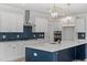 Stylish kitchen with white cabinets, a navy blue island, stainless steel appliances, and herringbone backsplash at 35 Accord Dr, Youngsville, NC 27596