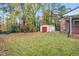Large backyard with a metal shed, green grass, fall foliage and mature trees at 710 Spring Ln, Sanford, NC 27330