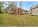 Rear exterior view of the home featuring a brick facade and spacious backyard at 710 Spring Ln, Sanford, NC 27330