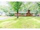 Charming brick home with well-kept lawn, carport, and a brick chimney, nestled among mature trees at 710 Spring Ln, Sanford, NC 27330