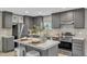 Modern kitchen features stainless steel appliances, gray cabinets, a kitchen island, and natural light from the window at 1235 Schloss Rd, Louisburg, NC 27549