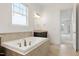Bright bathroom featuring a soaking tub with tile surround, dark vanity, and an entrance to another room at 1509 Heritage Reserve Ct, Wake Forest, NC 27587