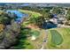 Expansive aerial shot of a golf course with manicured greens, mature trees, a serene lake, and a charming clubhouse at 1509 Heritage Reserve Ct, Wake Forest, NC 27587