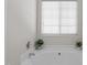 Bathroom features a jacuzzi style tub, a window with blinds, and is decorated with plants at 821 Stackhurst Way, Wake Forest, NC 27587