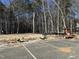 Cleared land ready for new construction in a wooded area near an empty parking lot, under a sunny blue sky at 1545 Crescent Townes Way, Raleigh, NC 27604