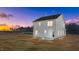 Backyard view showcasing a white home with a freshly seeded yard at twilight at 9154 Phoenix Ct, Middlesex, NC 27557