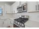 The kitchen features white cabinets and stainless steel microwave and gas range at 909 Montague Ave, Durham, NC 27703