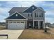 Two-story home featuring a gray exterior, stone accents, and a two-car garage on a landscaped lot at 105 Wilderness Ct, Mebane, NC 27302