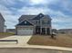 Two-story home featuring a gray exterior, stone accents, and a two-car garage on a landscaped lot at 105 Wilderness Ct, Mebane, NC 27302