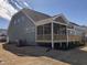 Green home's exterior showcasing a wooden deck and screened porch, all enhanced by a bright, sunny sky at 1600 Maelyn Way, Fuquay Varina, NC 27526