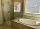Bright bathroom with a tiled surround tub with shower, and glass partition at 1600 Maelyn Way, Fuquay Varina, NC 27526