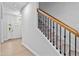 Bright hallway with light-colored wood floors and a staircase featuring a wooden handrail and black metal balusters at 2750 Lacy Holt Rd, Graham, NC 27253