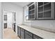 Butlers pantry features gray cabinets, glass cabinet doors, and stone countertop at 2750 Lacy Holt Rd, Graham, NC 27253
