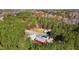 Aerial view showcases home, red barn, and surrounding wooded acreage at 3214 Tump Wilkins Rd, Stem, NC 27581