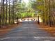 Private property entrance featuring a decorative metal gate amidst a wooded landscape at 3214 Tump Wilkins Rd, Stem, NC 27581