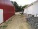 Side yard view of the property featuring stone landscaping and a barn-style shed with corrugated red metal siding at 3214 Tump Wilkins Rd, Stem, NC 27581