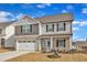 Charming two-story home featuring stone accents, neutral siding, an attached two-car garage, and a bright blue front door at 517 Southwick Pl, Mebane, NC 27302
