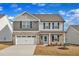 Charming two-story home featuring stone accents, neutral siding, an attached two-car garage, and a bright blue front door at 517 Southwick Pl, Mebane, NC 27302