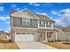 Charming two-story home featuring stone accents, neutral siding, an attached two-car garage, and a bright blue front door at 517 Southwick Pl, Mebane, NC 27302