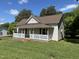 Charming home featuring a welcoming porch, neutral siding, brown roof, and surrounded by lush greenery on a sunny day at 1200 Carolina St, Graham, NC 27253