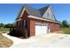Side view of a brick home featuring a white garage door, concrete driveway, and meticulously maintained landscaping at 7575 Sweetwater Dr, Nashville, NC 27856