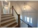 Elegant foyer featuring a staircase with wooden steps, white risers, and a stylish, modern spherical pendant light at 7575 Sweetwater Dr, Nashville, NC 27856