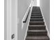 Carpeted stairs with white risers and wooden handrail offer an inviting transition to the next level at 91 Laramie Ln, Selma, NC 27576