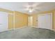 Bright bedroom with neutral carpet, yellow walls, ceiling fan, closet, and doors at 1146 Rogers Rd, Graham, NC 27253