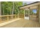 View of a screened porch with wood floors and railings surrounded by dense, green trees at 115 Arundel Dr, Archer Lodge, NC 27527