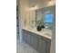 Bright bathroom featuring double sinks, white countertop, gray vanity, and large mirror at 1233 Azalea Garden Cir, Raleigh, NC 27603