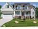 Inviting home featuring a manicured lawn, covered porch, brick accents and a white garage door at 1233 Azalea Garden Cir, Raleigh, NC 27603