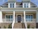 Charming front porch featuring brick accents, white railings, and a stained wood front door at 1233 Azalea Garden Cir, Raleigh, NC 27603