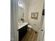 Chic powder room with a modern vanity, accent mirror, and warm wood-look flooring at 1233 Azalea Garden Cir, Raleigh, NC 27603